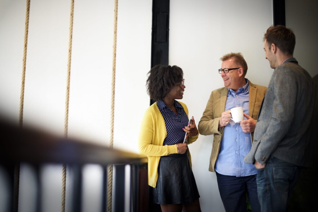Three colleagues chatting over coffee in the office